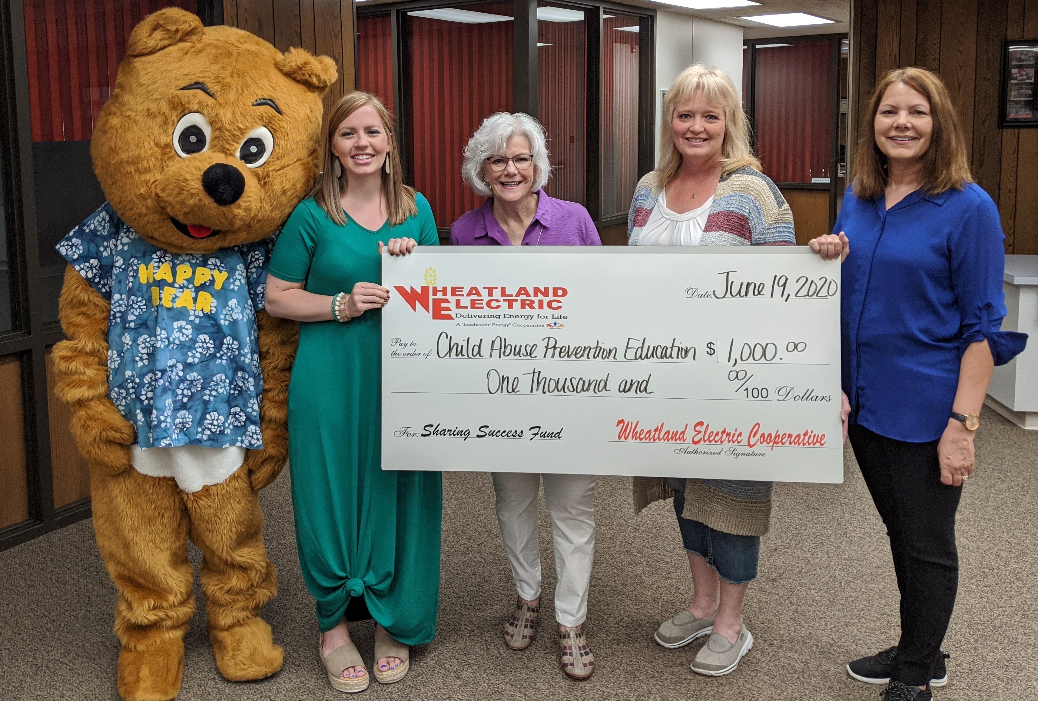 Several Board Members from CAPE gathered to accept their $1,000 Sharing Success Grant from Wheatland Electric on June 19, 2020. Pictured from left to right are Happy Bear (Mary Johnson), Regan Reif, Member Services and Key Accounts Manager for Wheatland Electric, Judy Johnson, CAPE Director, Shala Ehrlich, CAPE Treasurer, and Sheryl Neeland, CAPE Board President.